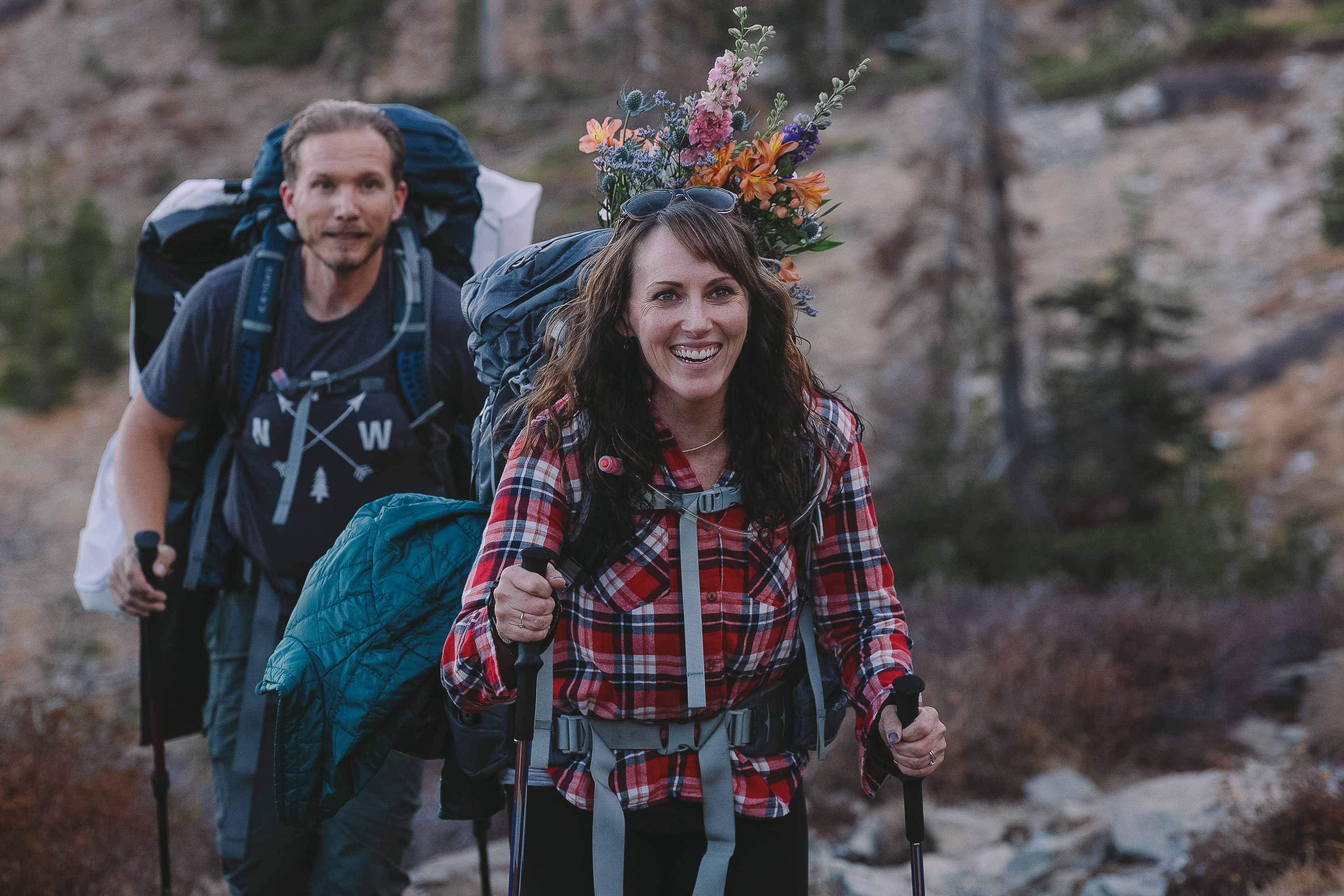 Couple with hiking poles and packpacks on hiking in the mountains to their elopement location