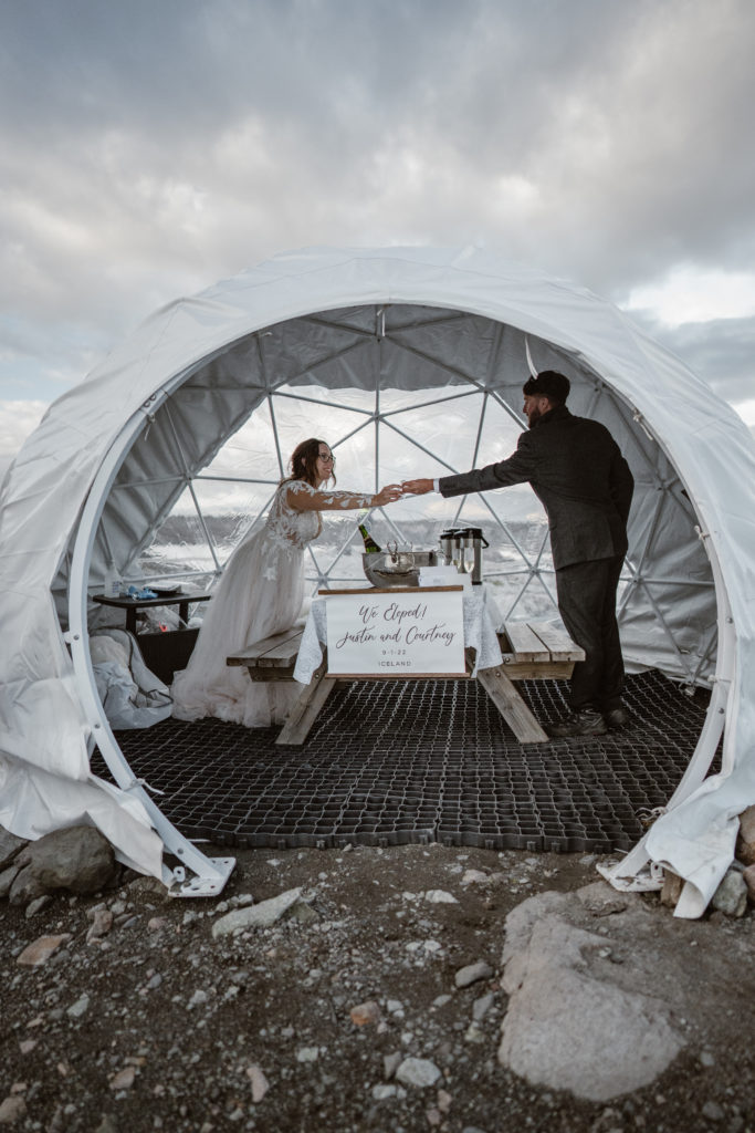 A couple toasts to their marraige in an igloo during their Iceland elopement