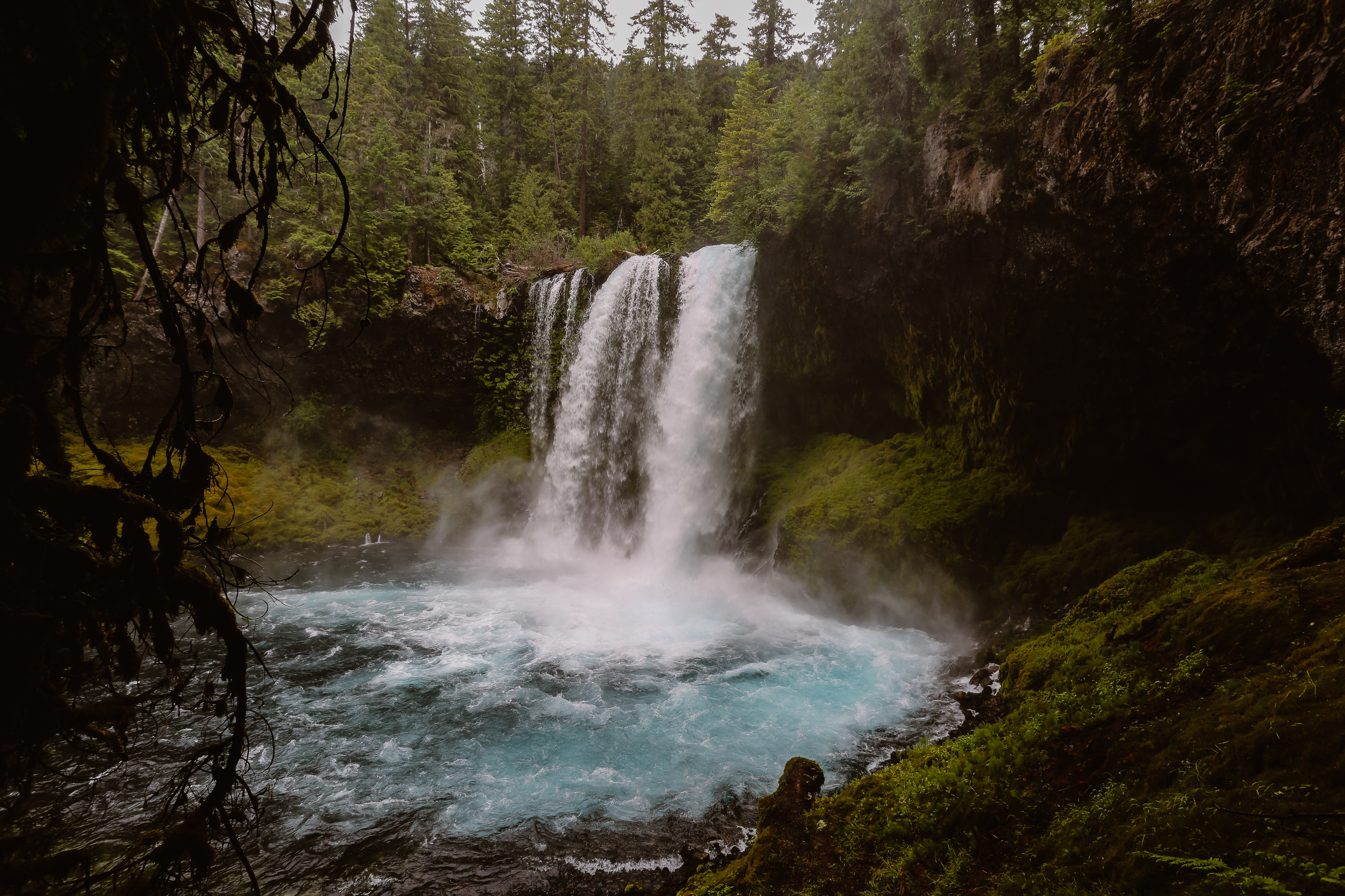 a turqupoise blue waterfall outside of bend oregon surrounded by evergreens