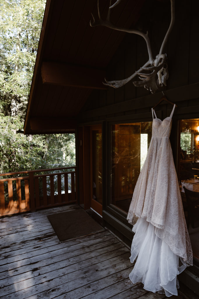 A white wedding dress hangs on a balcony during an Alaska elopement