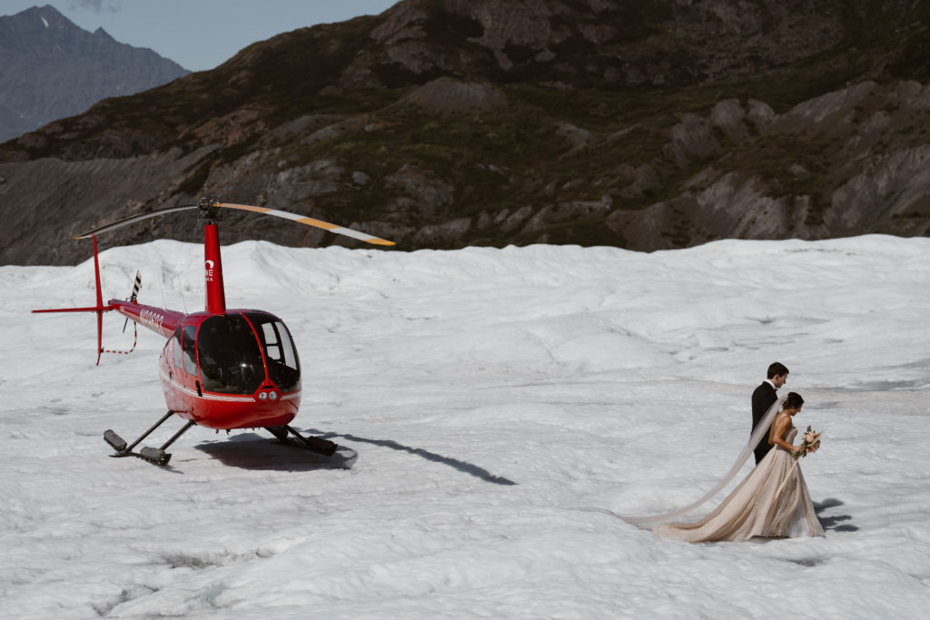 A couple walks away from their helicopter in Alaska during their Alaska elopement