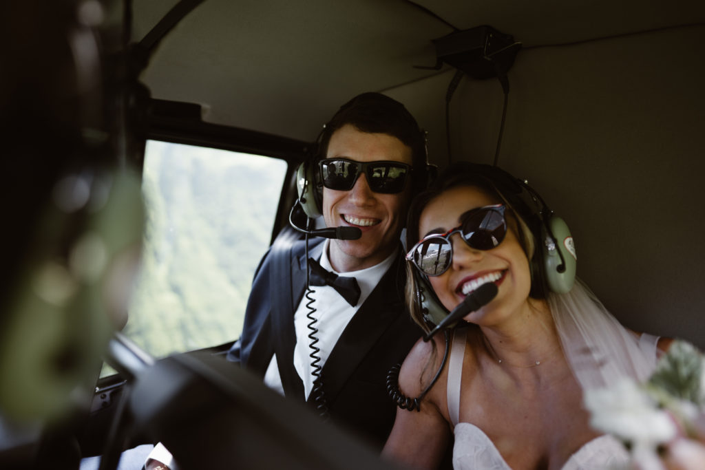 A couple smiles for a photo in their helicopter during their Alaska elopement