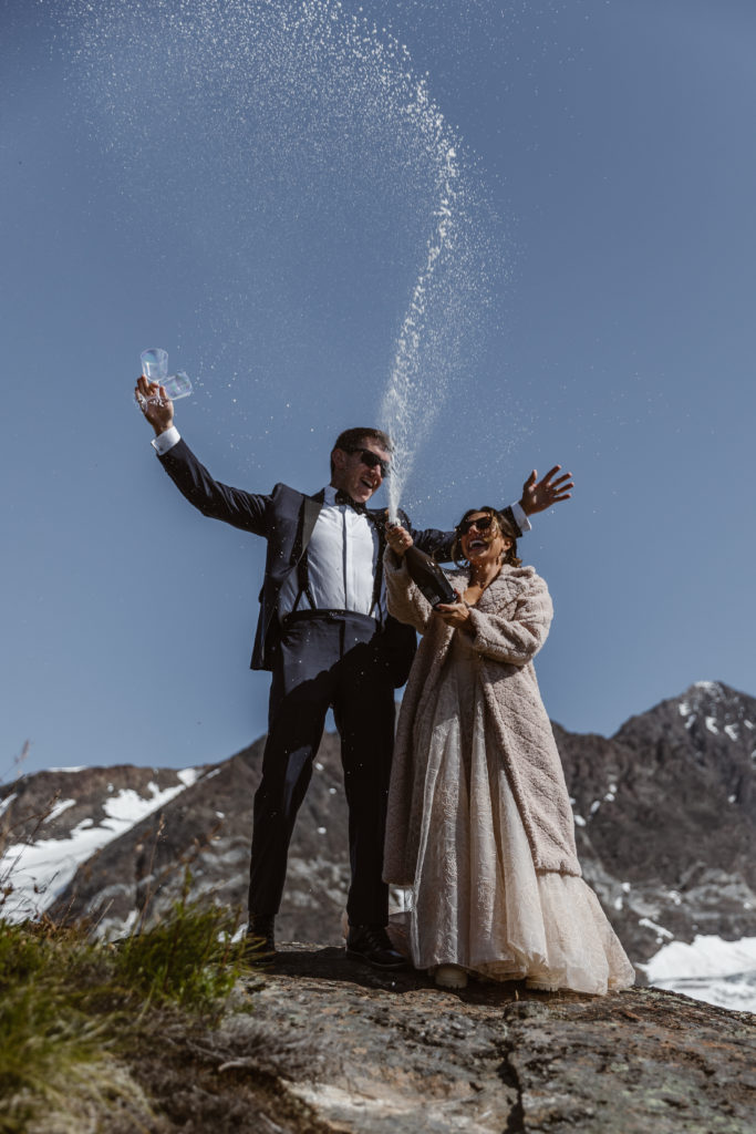 A couple celebrates with a bottle of champagne during their Alaska elopement