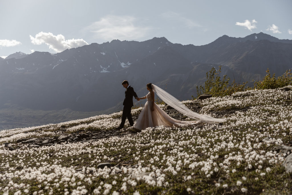 A couple walks in the wildflowers during their Alaska elopement