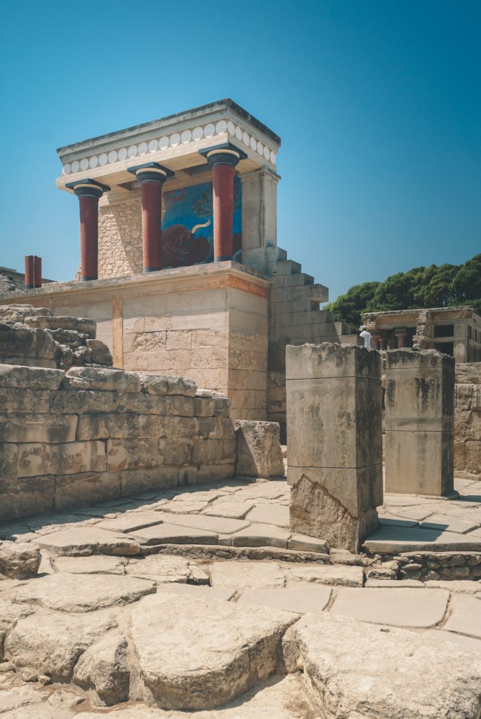 A historic structure with three pillars stands at ancient ruins in Heraklion, Crete