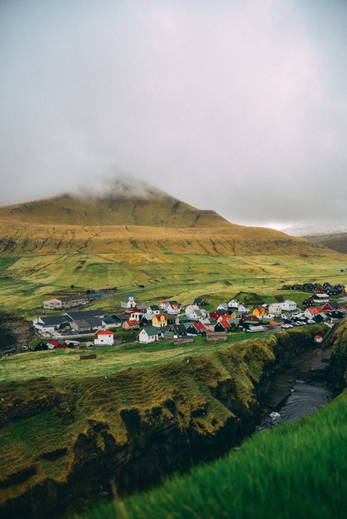 A small town with red and white colored homes situated on the edge of a cliff in the Faroe Islands