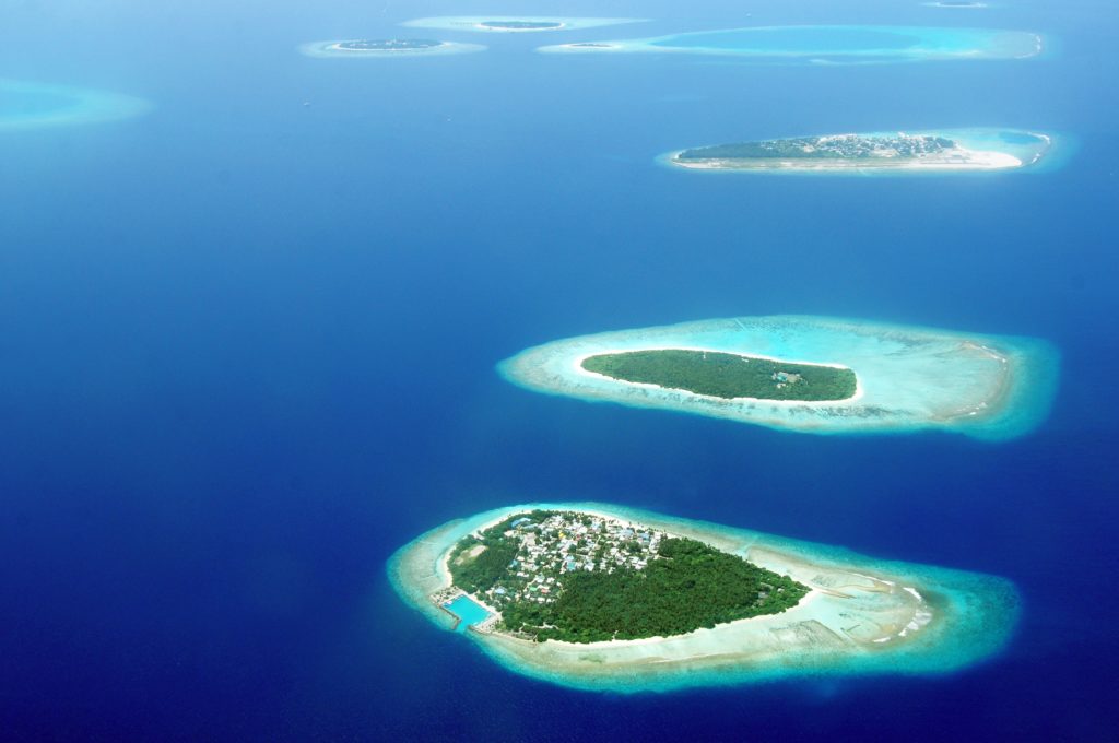 Small green islands scattered in the midst of deep blue waters in the Maldives
