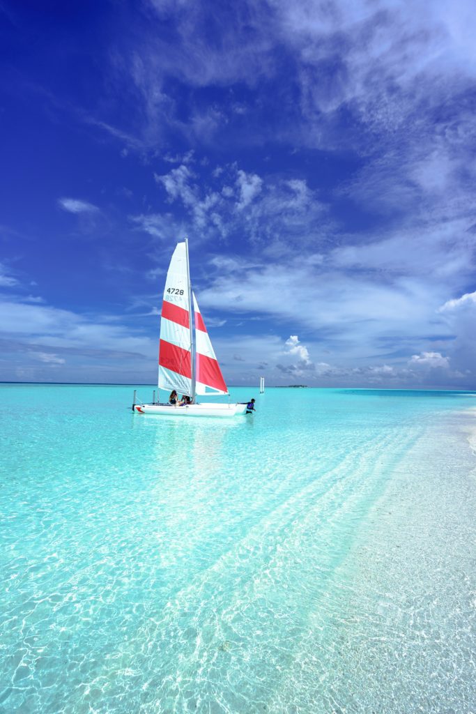 A sailboat with red and white colors in the clear blue water in the Maldives
