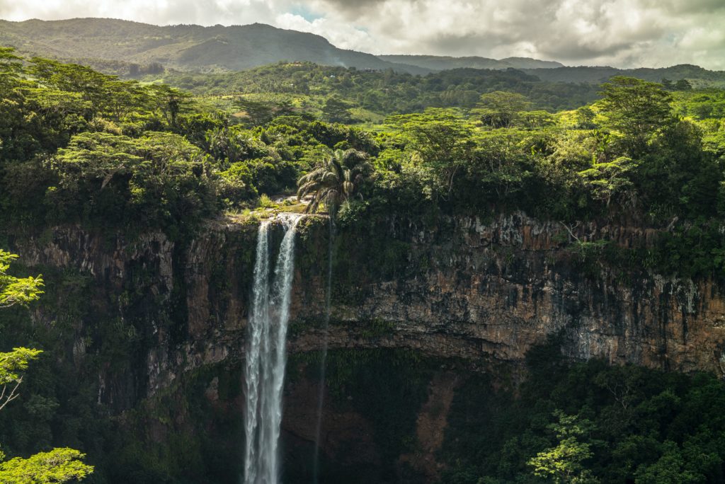 A waterfall runs over a cliff in the middle of a jungle at Black River Gorges National Park in Mauritius