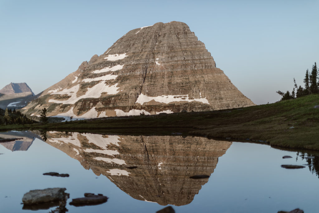 A snowy mountain stands in the background, reflected in the alpine lake below