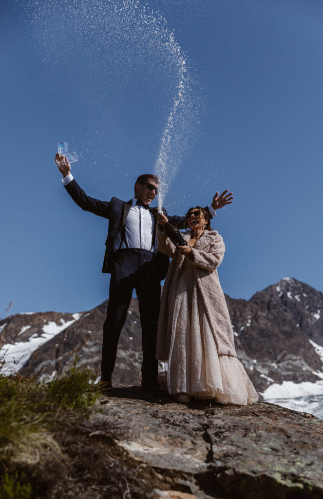 A couple pops a bottle of champagne during their Alaska elopement