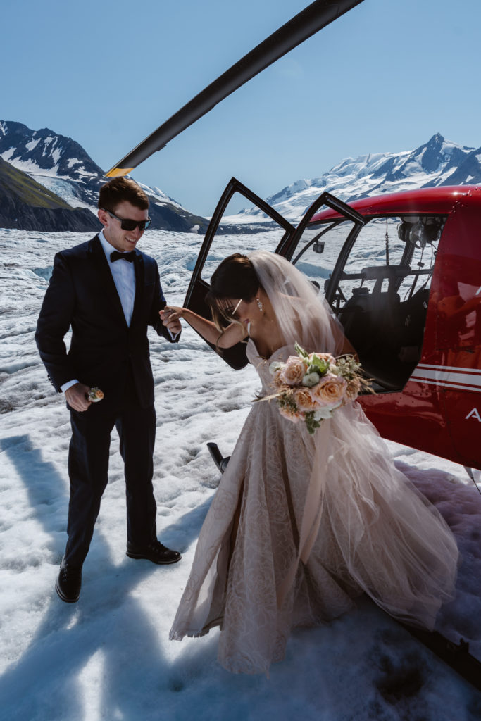A couple gets out of a helicopter in Alaska, during their Alaska elopement